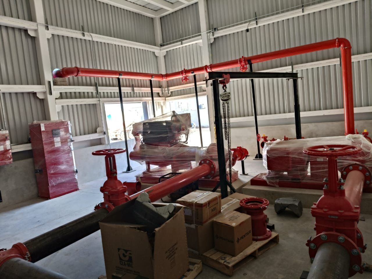 Fire pump room during installation, with red piping, valves, and materials on site.