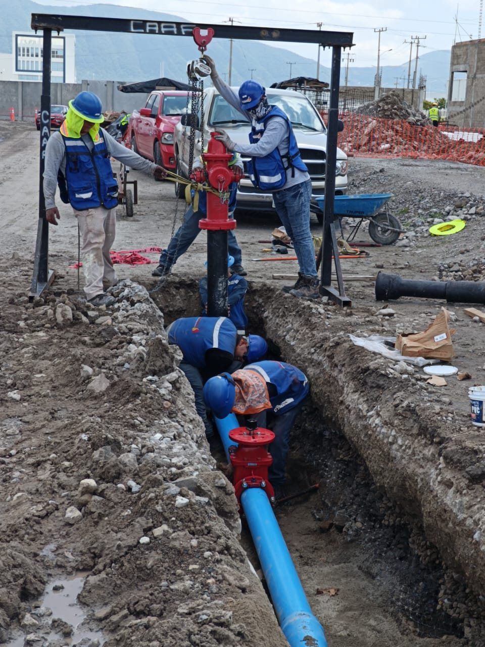 Cuadrilla instala un hidrante sobre la tubería enterrada dentro de la zanja.