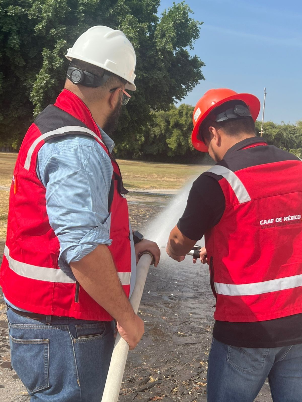 CAAF de México technicians control the water discharge from a hose during a test.