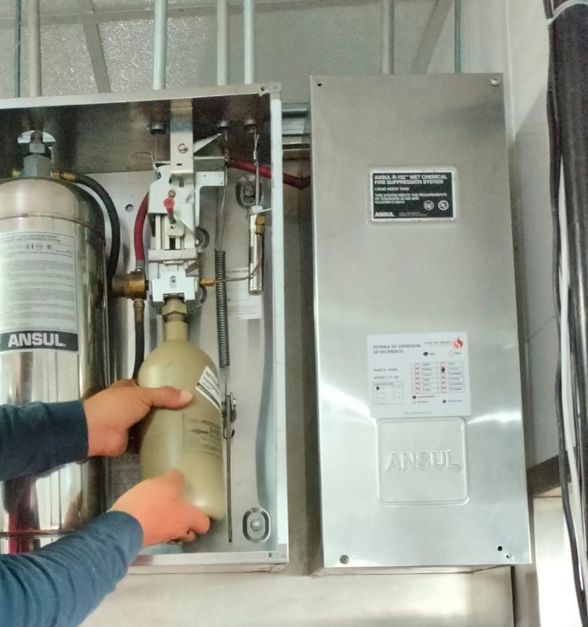 Technician places the release mechanism cartridge in the enclosure of an Ansul system.