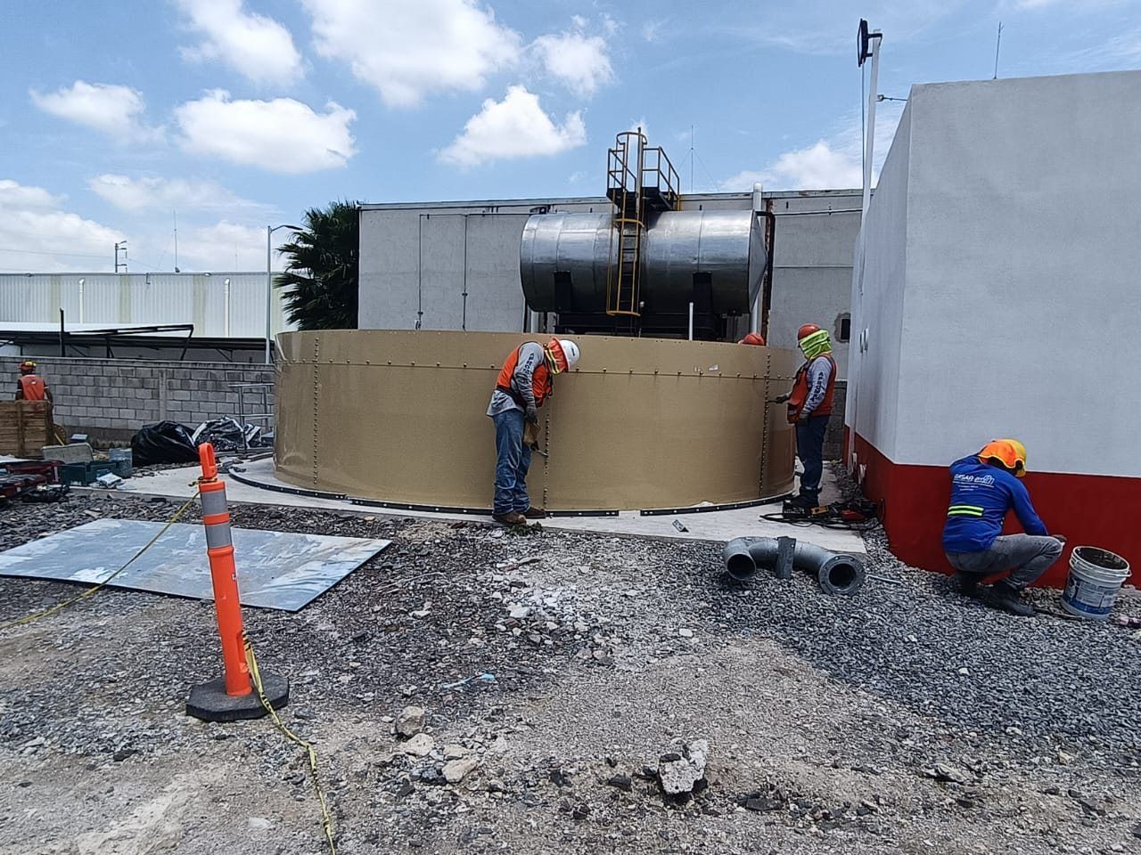 A crew bolts the panels of the first ring of a fire water storage tank.